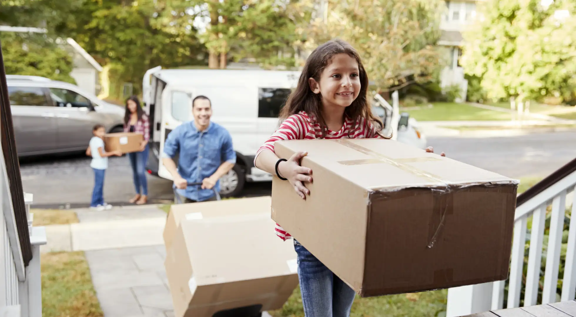 An excited family moves boxes into their new home.