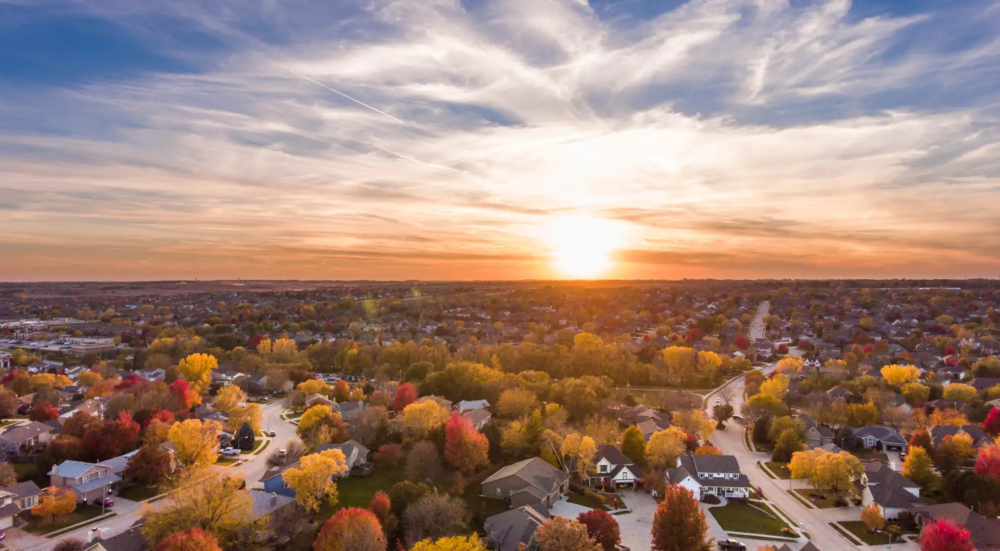 Aerial view of a suburban neighborhood backdropped by a setting sun.