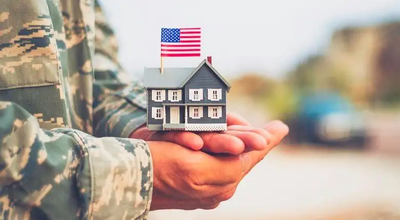 military service member holding a small home with an american flag