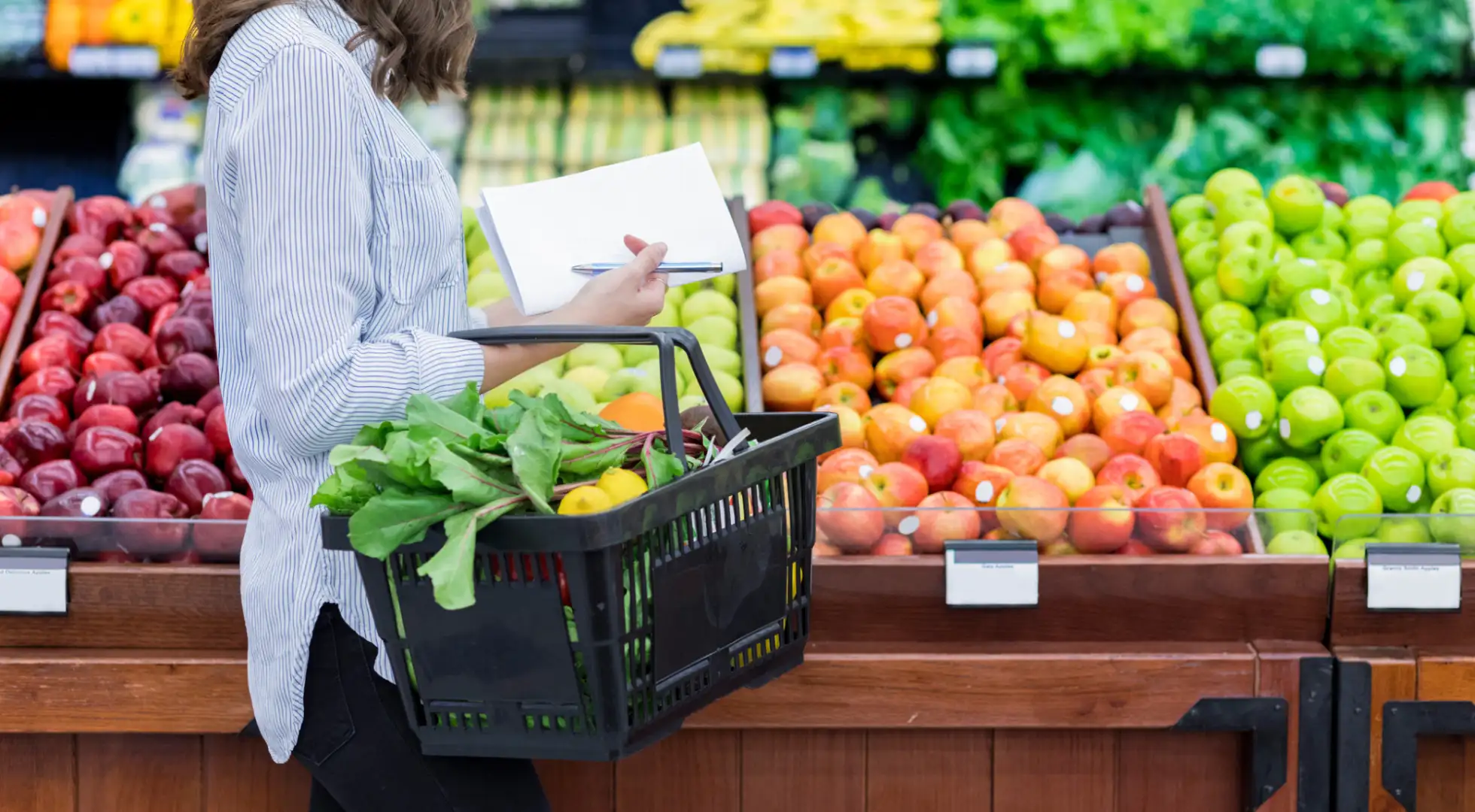 woman walking by produce in grocery store