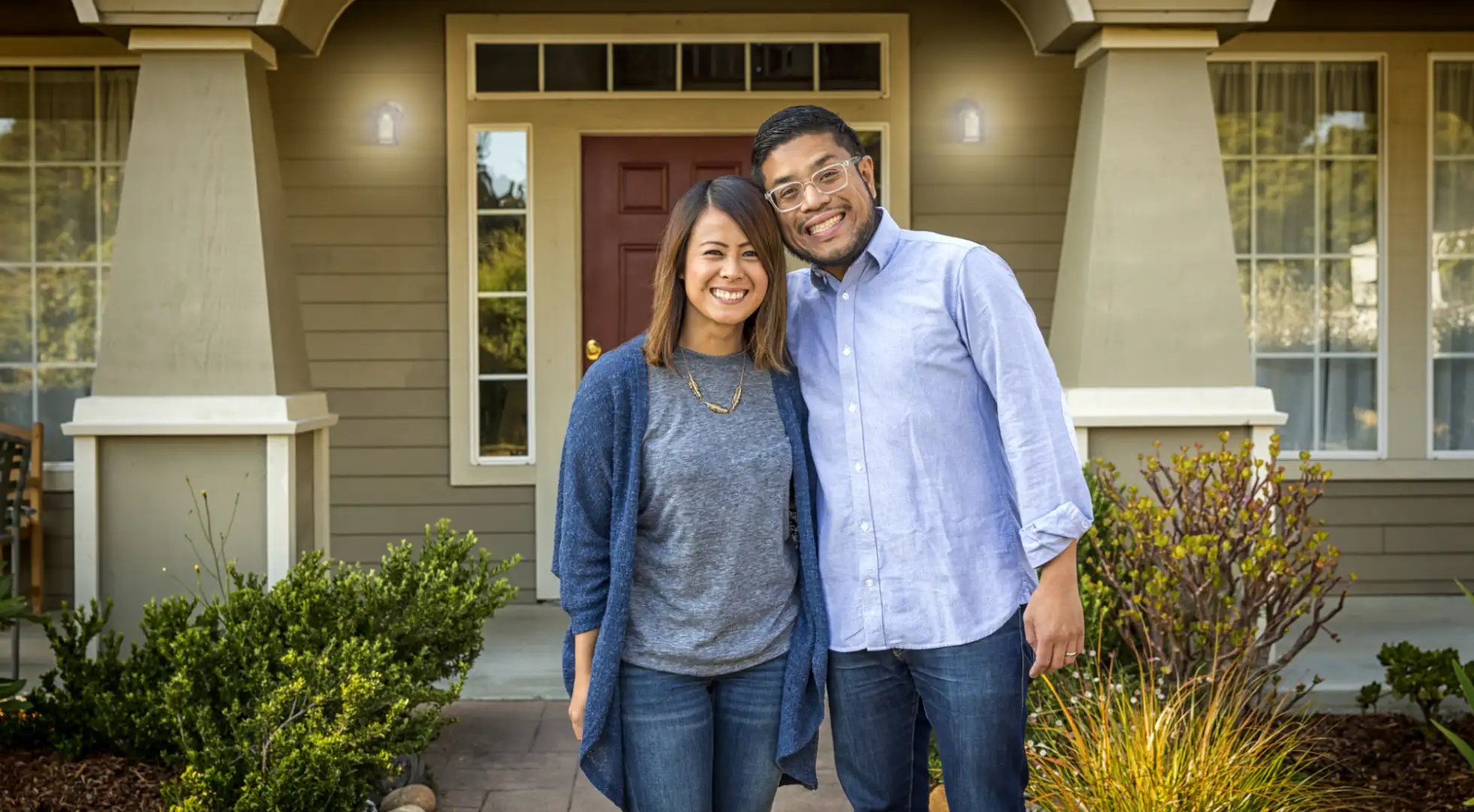 Couple standing in front of a house. Learn about student loan mortgage qualification guidelines.