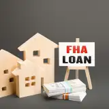 Wooden model houses with a sign reading "FHA LOAN".