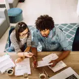 A couple reviewing documents and discussing their down payment options on a laptop.