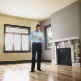 A man conducts a home appraisal, taking notes on a clipboard in an empty room.