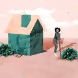 A woman standing in front of a paper house with umbrella.