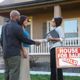 Couple shakes realtor's hand after buying house.