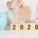 cut-out of a home over blocks reading 2026 and a blue piggy bank