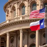 US and Texas flags flying in front of the Texas State Capitol