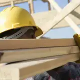 Construction worker carrying wood