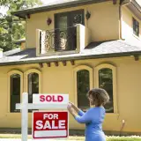 real estate agent placing sold sign on home