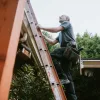 How to Use a VA Mortgage to Fund Your Fixer-Upper Projects A man climbs a ladder to his home's roof