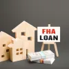 Wooden model houses with a sign reading "FHA LOAN".