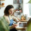 A self-employed woman working on her laptop in a home office with art supplies.