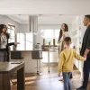 A multi-ethnic family being shown a modern kitchen by a real estate agent in a bright, stylish home.