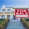 A home with a "For Sale" sign in the front yard, representing a foreclosed home sold by HUD.