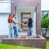 Real estate agent and couple in front of a house.