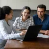 Couple sitting with mortgage loan officer talking about refinancing.