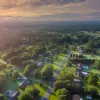 Rural community with homes that are spaced out and surrounded by lots of trees and rolling pasture.