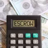 What is Mortgage Escrow? 'Escrow' displayed on a calculator screen on top of a stack of money