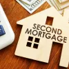 Small home cutout on desk that says, 'Second Mortgage'.