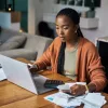 A woman with a calculator deciding whether to refinance