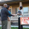 Couple shakes realtor's hand after buying house.