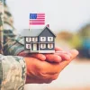 military service member holding a small home with an american flag