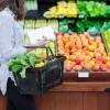 woman walking by produce in grocery store