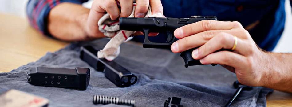 A guy cleaning his glock pistol and cleaning tools on the table.