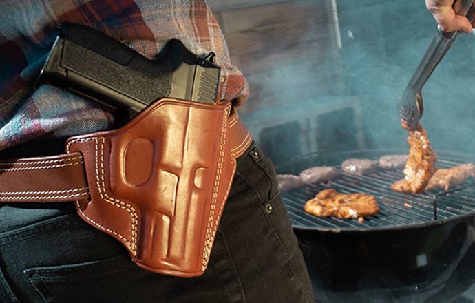 A man with an OWB holster barbecuing