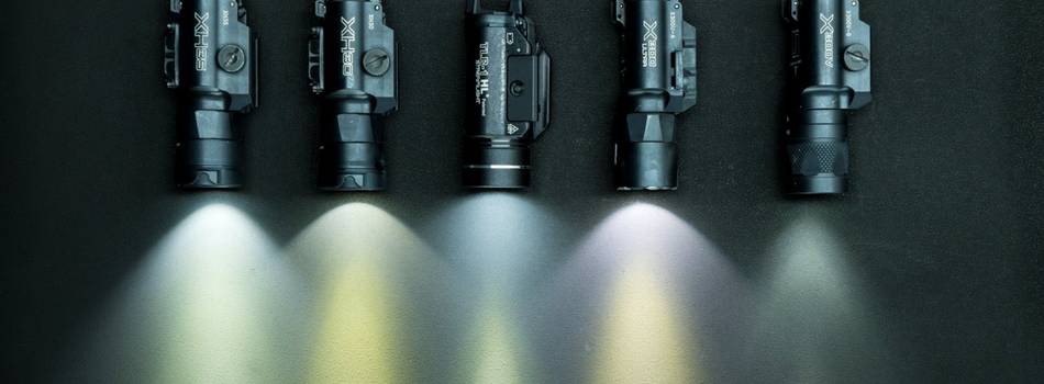 A set of 5 tactical flashlights for handguns on the table with light on.