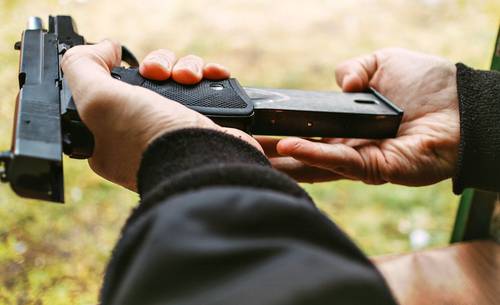 A guy reloading his pistol with a new magazine