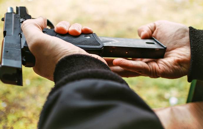 A guy reloading his pistol with a new magazine