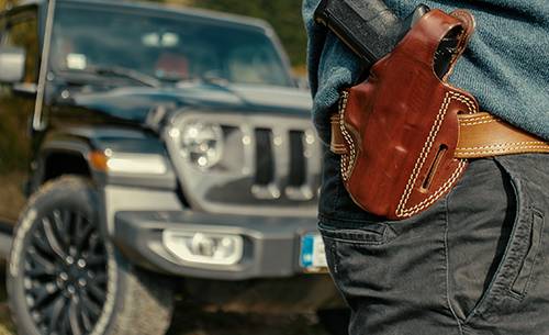 A gun in front of a car with a holster and gun