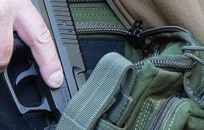 Man drawing a firearm from his concealed carry bag