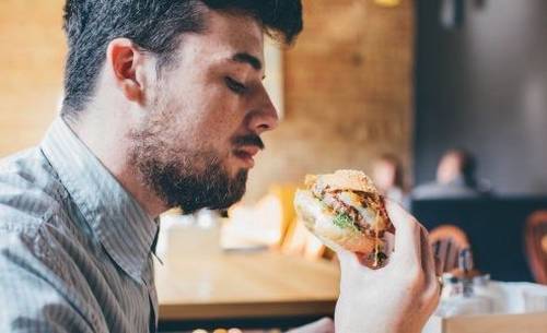 A man about to eat a  hamburger which he holds in his hand