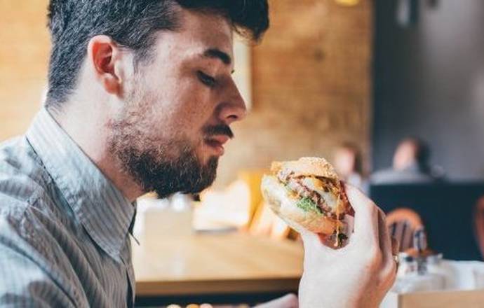 A man about to eat a  hamburger which he holds in his hand