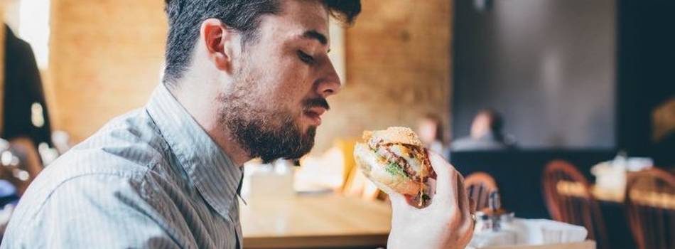 A man about to eat a hamburger which he holds in his hand