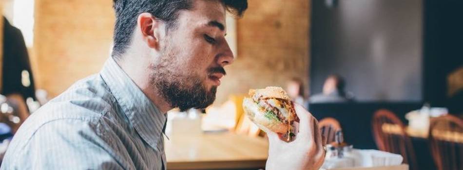 A man about to eat a  hamburger which he holds in his hand