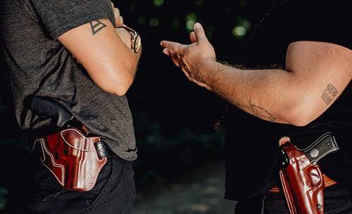 two guys talking about something important with holsters on