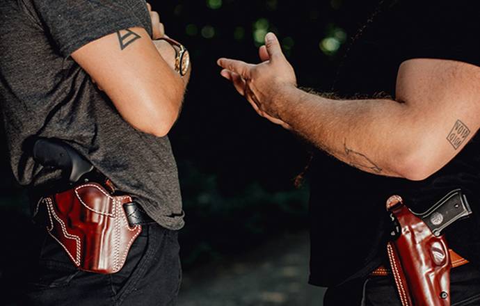 two guys talking about something important with holsters on