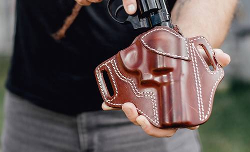 a guy inserting his j frame revolver in a holster