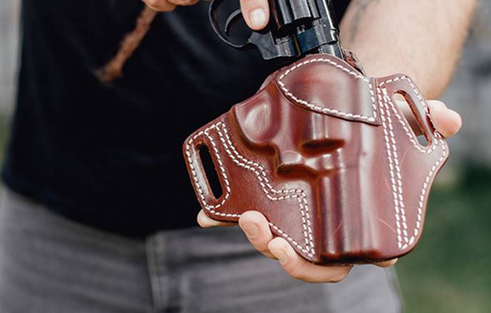 a guy inserting his j frame revolver in a holster