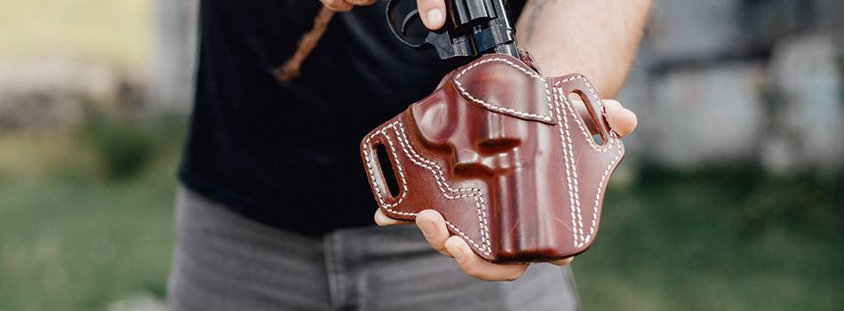 a guy inserting his j frame revolver in a holster