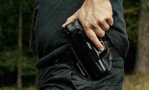 A guy drawing his gun from a left handed holster