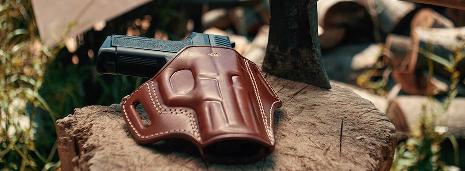 An OWB holster lying on a tree trunk with an axe next to it