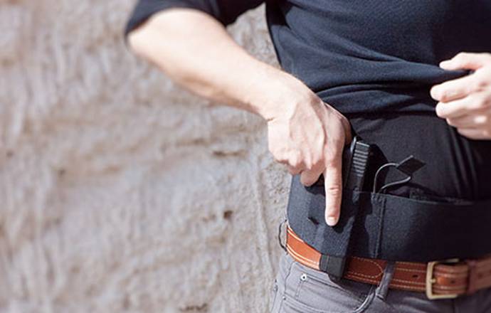 A man drawing a Glock from his concealed carry fanny pack