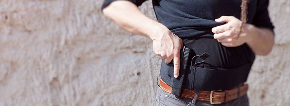 A man drawing a Glock from his concealed carry fanny pack