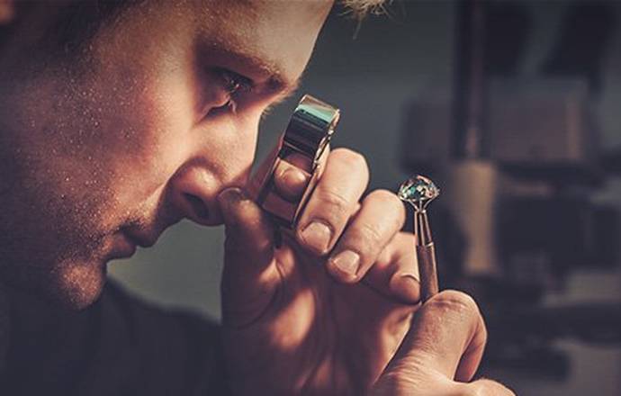 Jewelry expert checking a diamond through a magnifying glass in his workshop.