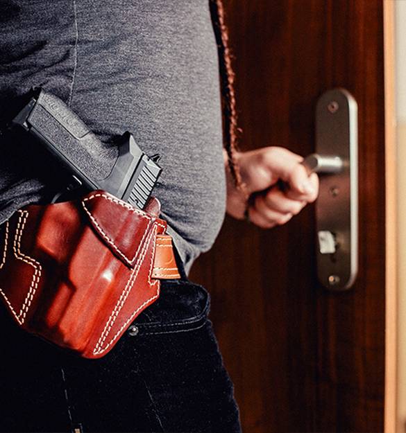 A guy with a chest holster tucked under a red checkered shirt looking into distance